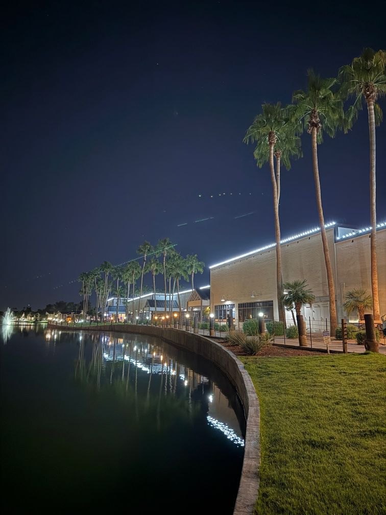 A waterfront Arizona shopping and dining center outlined in crisp white C9 LED roofline lights at night, reflected in the lake.
