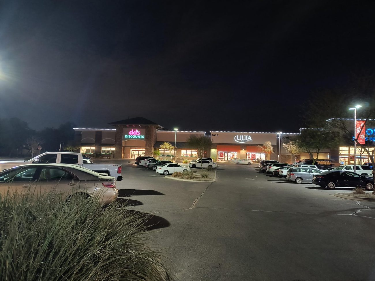 A large shopping center with multiple storefronts lined in roofline lighting.