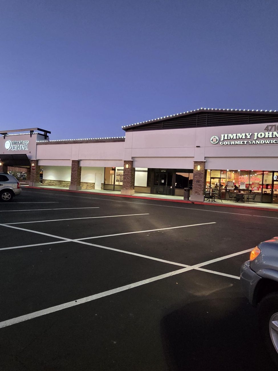Commercial center roofline lighting glowing against a deep blue dusk sky.