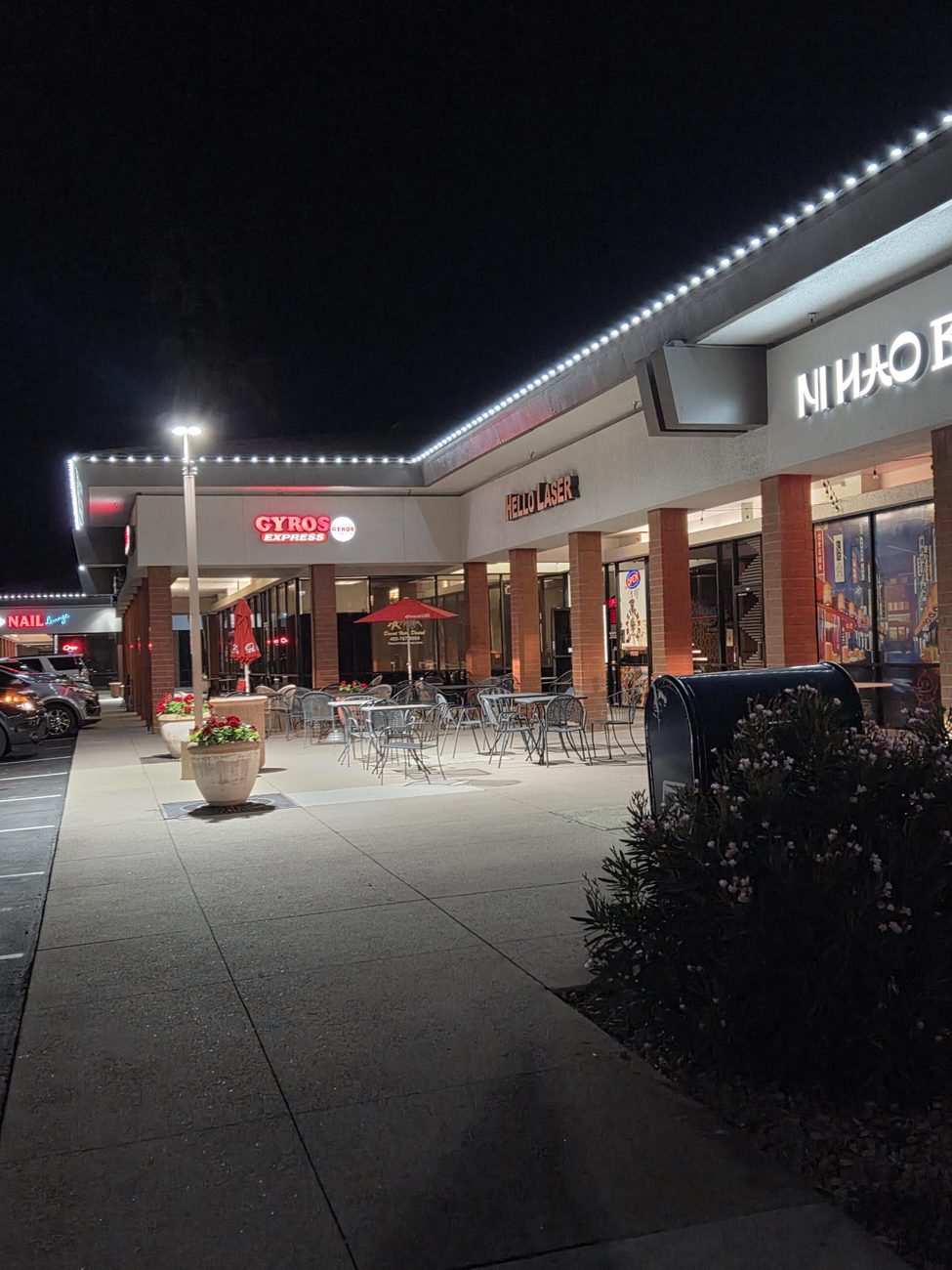 Roofline lights over a restaurant patio at a commercial strip center.